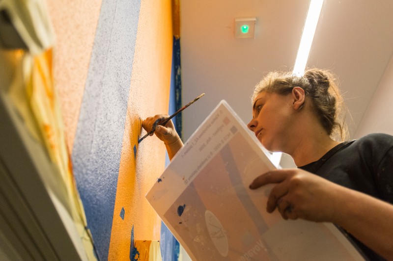 Artist painting wall designs in a modern Proximo office building on Przyokopowa street in Warsaw | PROXIMO | Portfolio