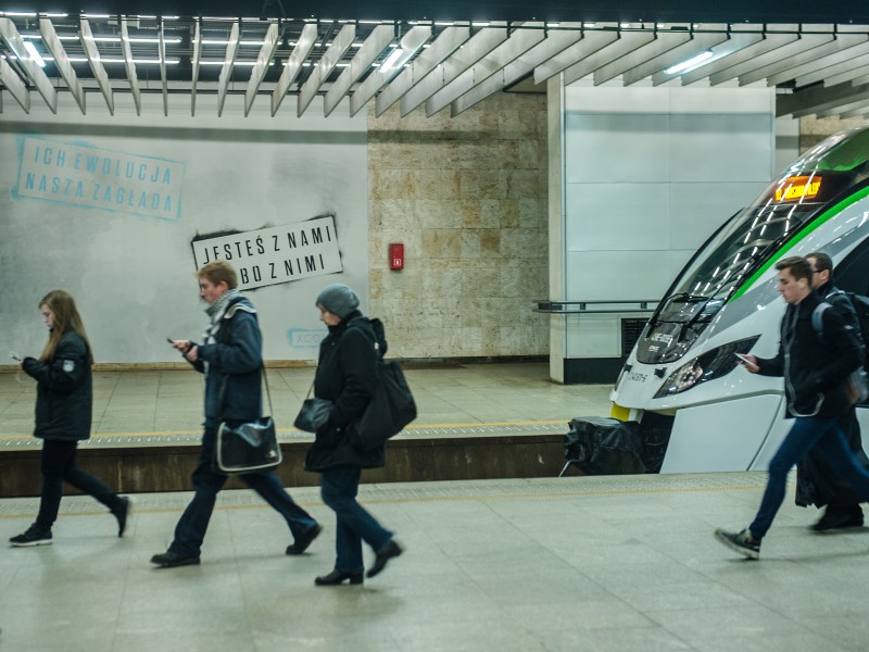 Ein großflächiges Kunstwerk als Werbung des Spiels XCOM2 im Bahnhof Warszawa Srodmiescie in Warschau Du bist mit uns oder mit ihnen | Gra XCOM2 na PKP Śródmieście | Portfolio